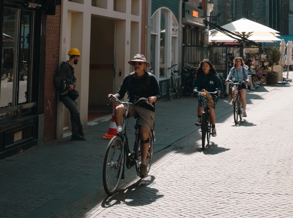 Three cyclists riding through a sunlit street in Haarlem