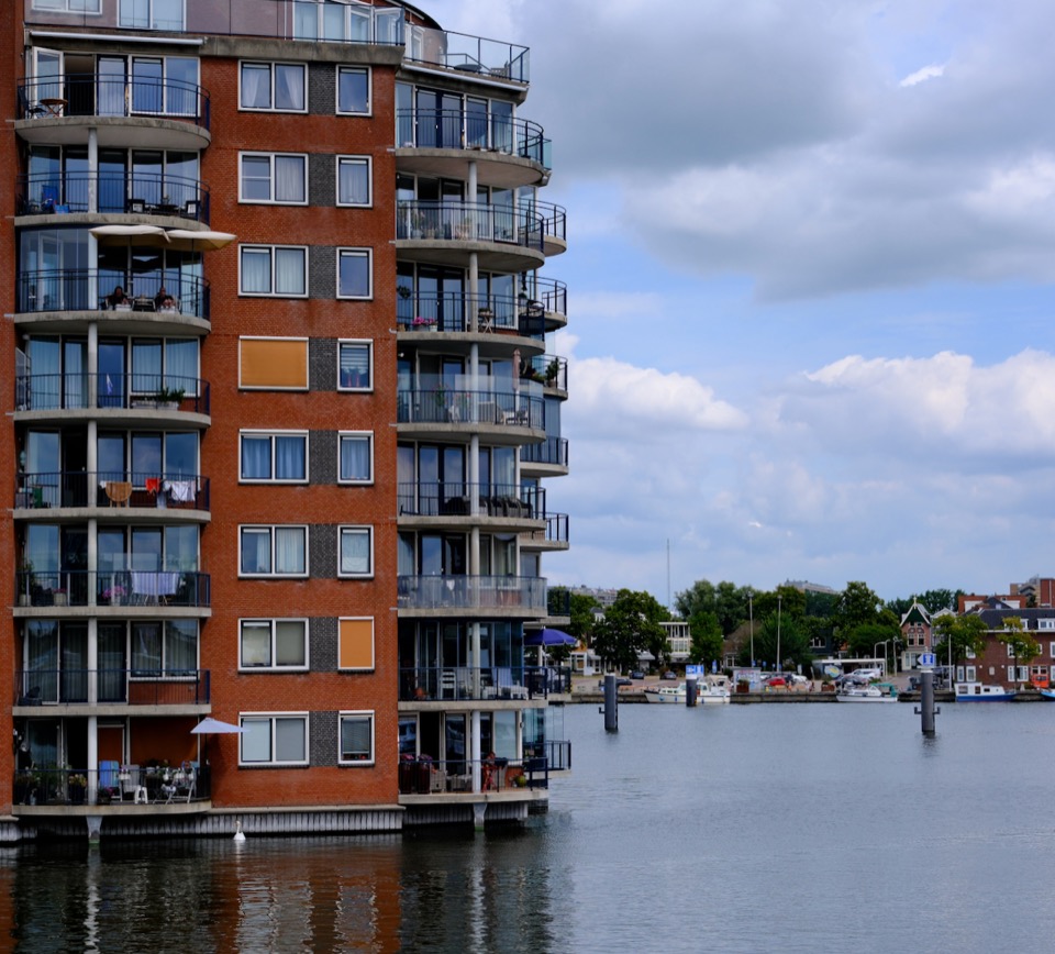 Waterside apartments and boats beneath broad summer clouds